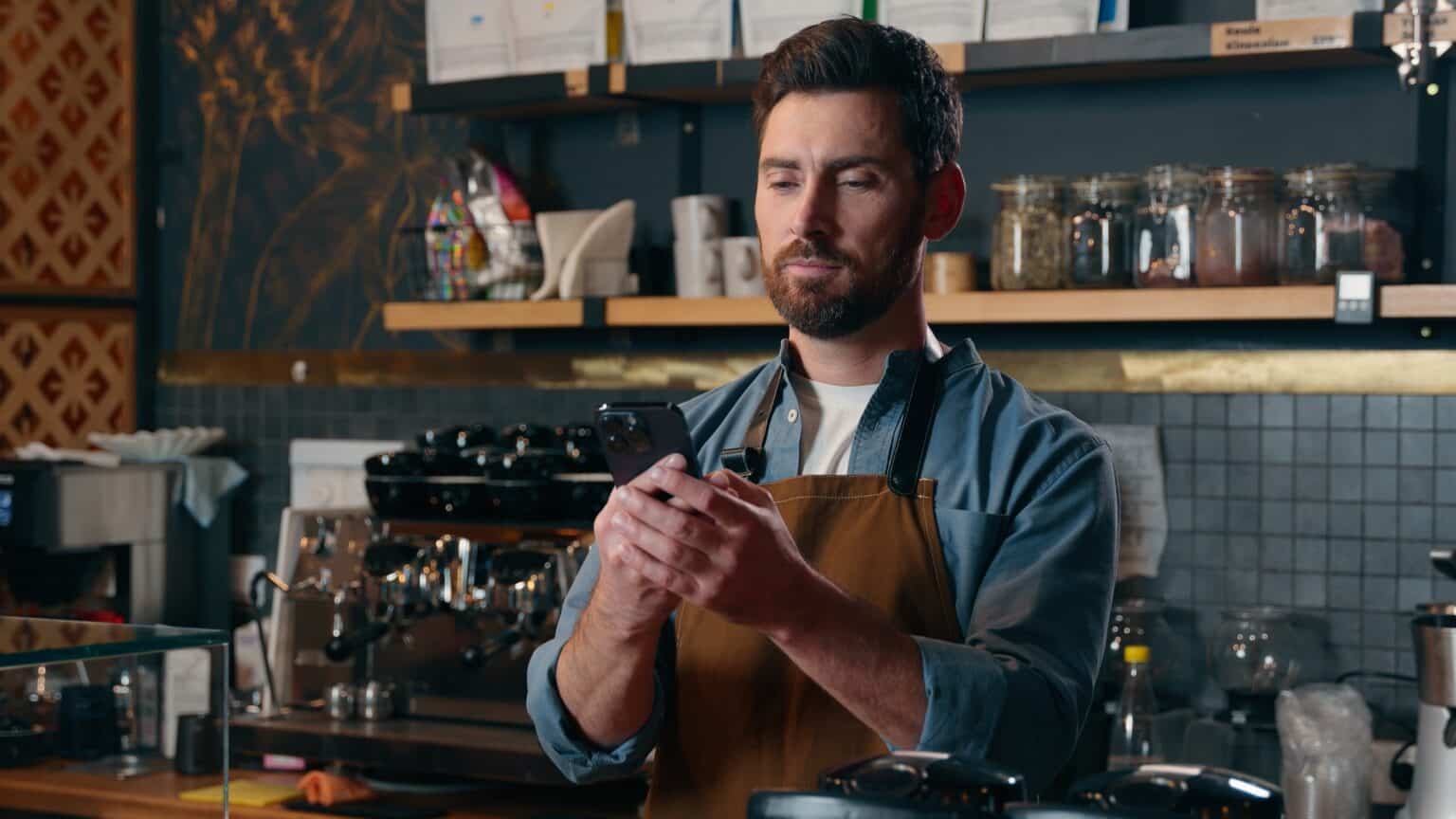 Kafé-eier med smarttelefon bak disken