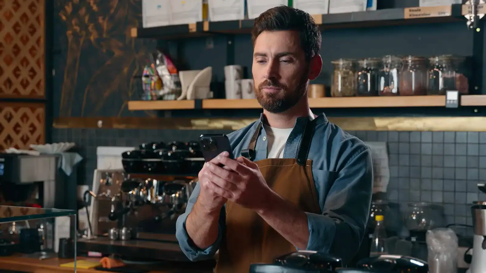 Kafé-eier med smarttelefon bak disken