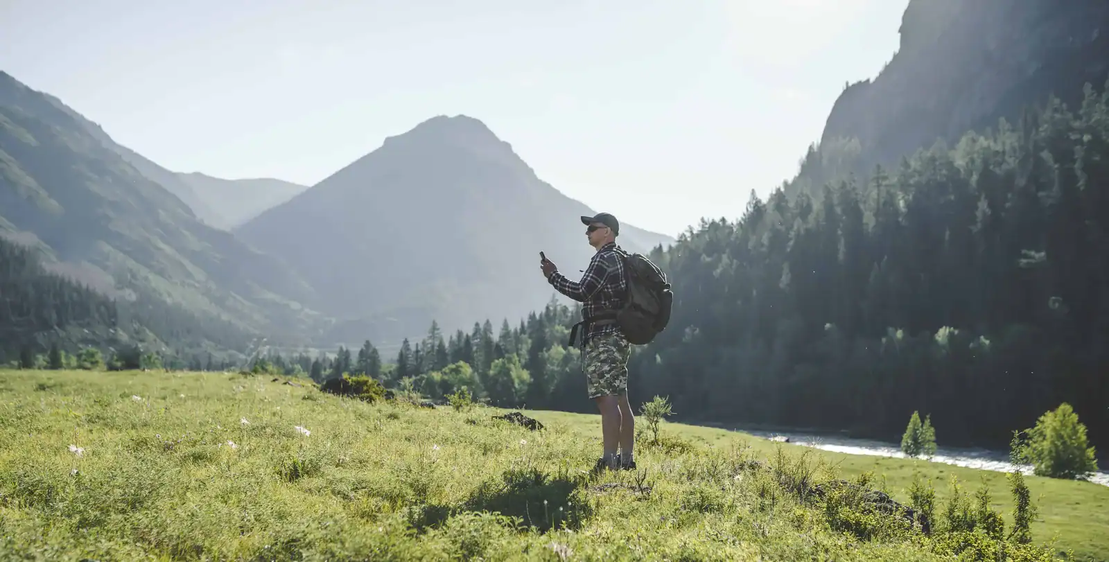 Mann sjekker mobiltelefonen i norsk fjellandskap