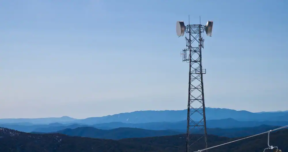 Mobilmast på en fjellrygg med fjell i bakgrunnen