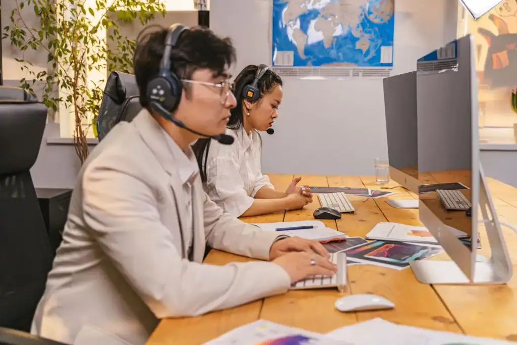 Kundeservicemedarbeidere med headset ved arbeidsplassene sine